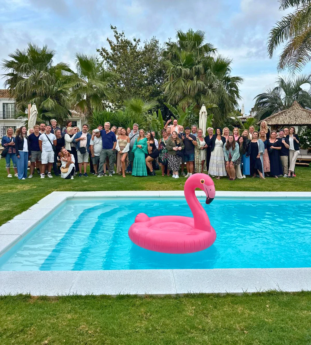Reaktin tiimi koolla uima-altaalla Aurinkorannikolla — altaassa vaaleanpunainen Reakt-flamingo